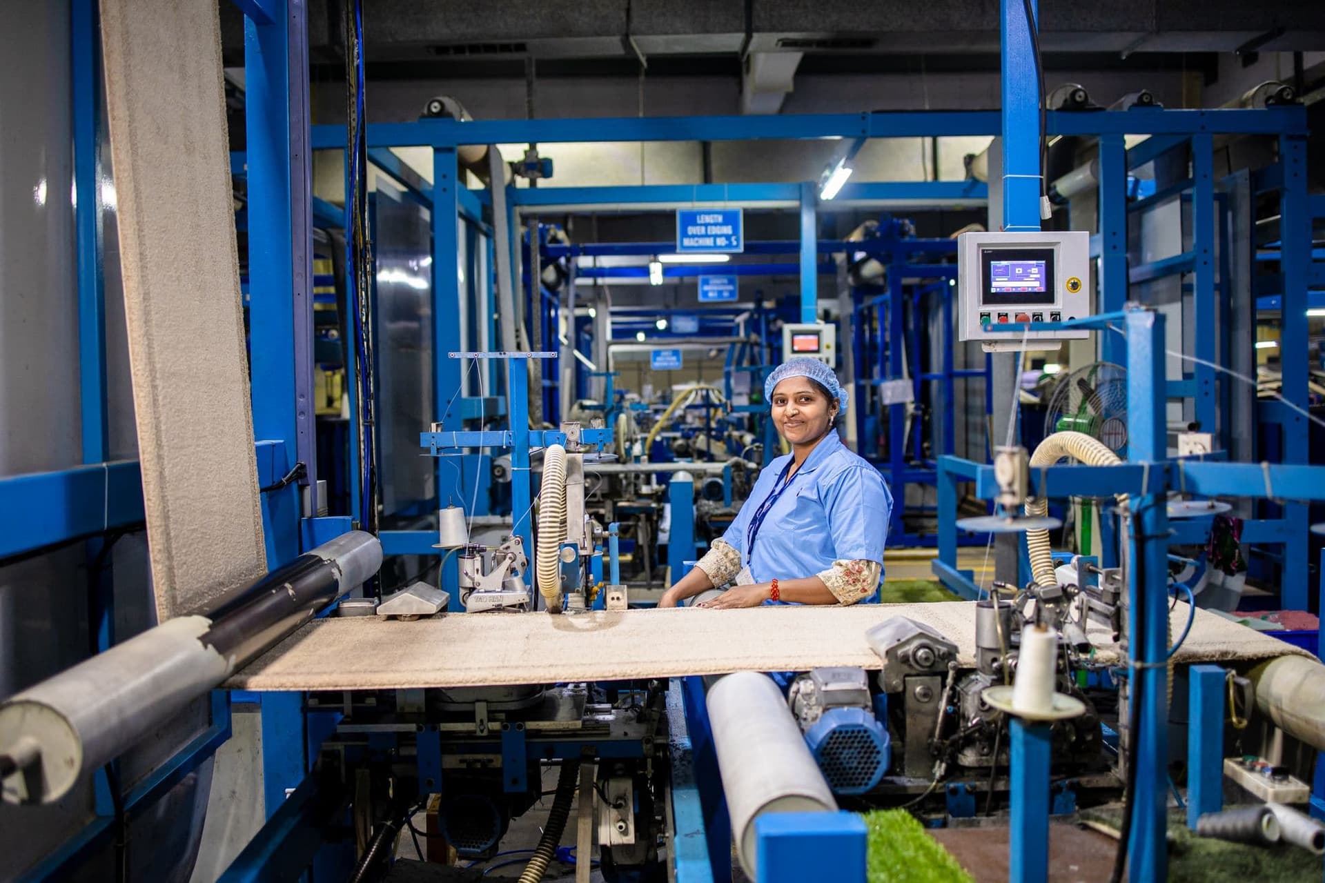 Factory worker smiling beside industrial machinery